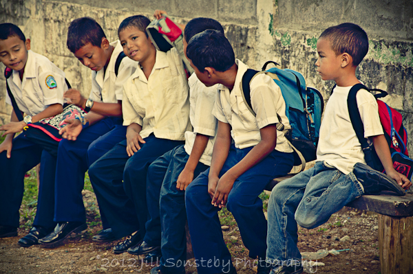 A group of school kids sitting on a bench in Utila, Honduras