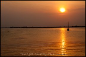 Sunset in Utila, Honduras with a boat in the water.