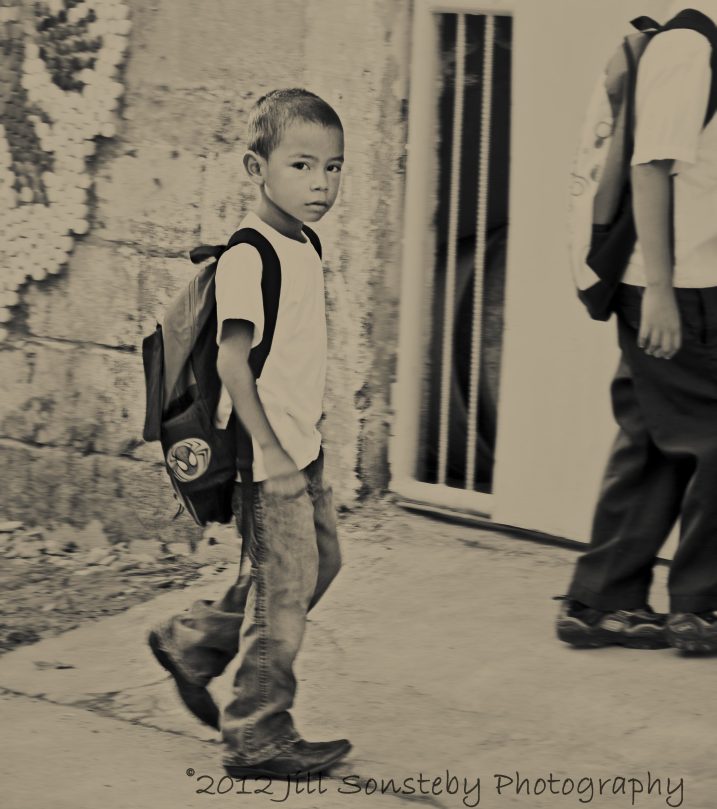 A little boy without a uniform walks into the school gate in Utila, Honduras.