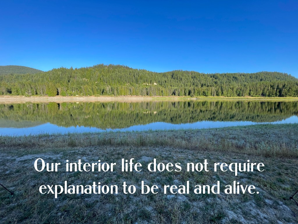 Tree filled range reflected in calm river.